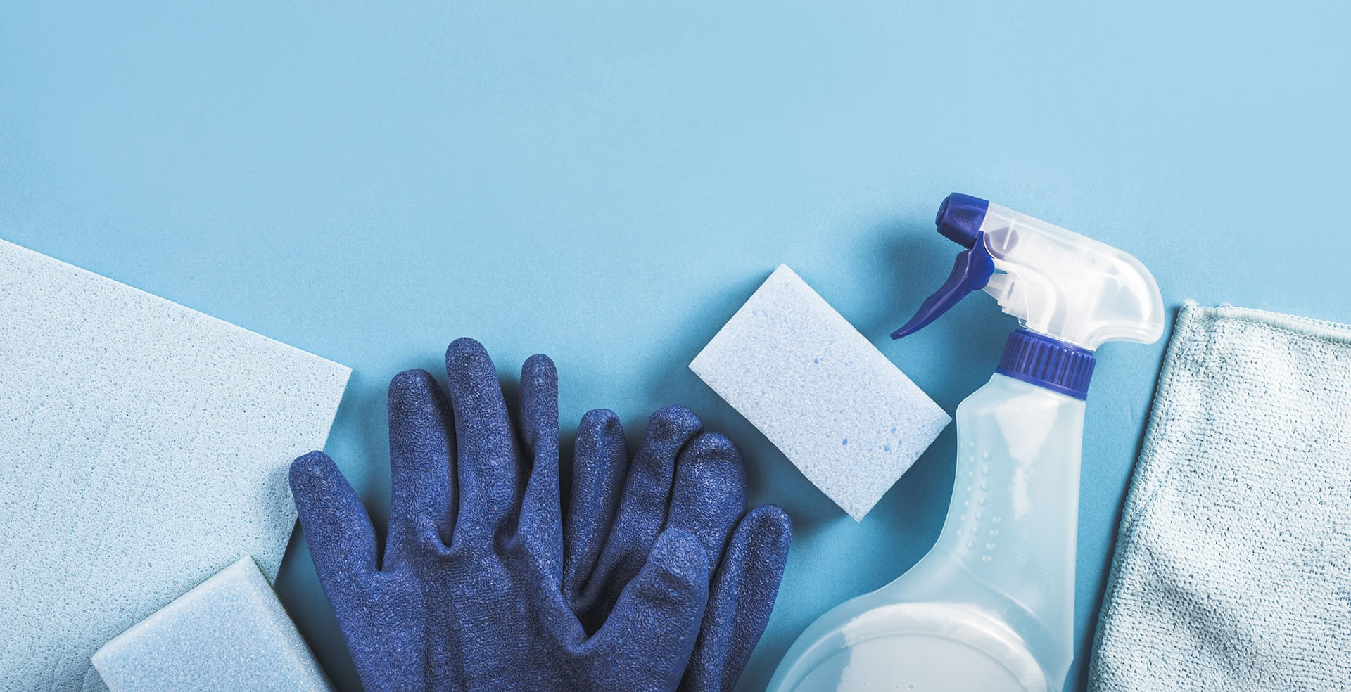 high-angle-view-spray-bottle-gloves-sponge-blue-background